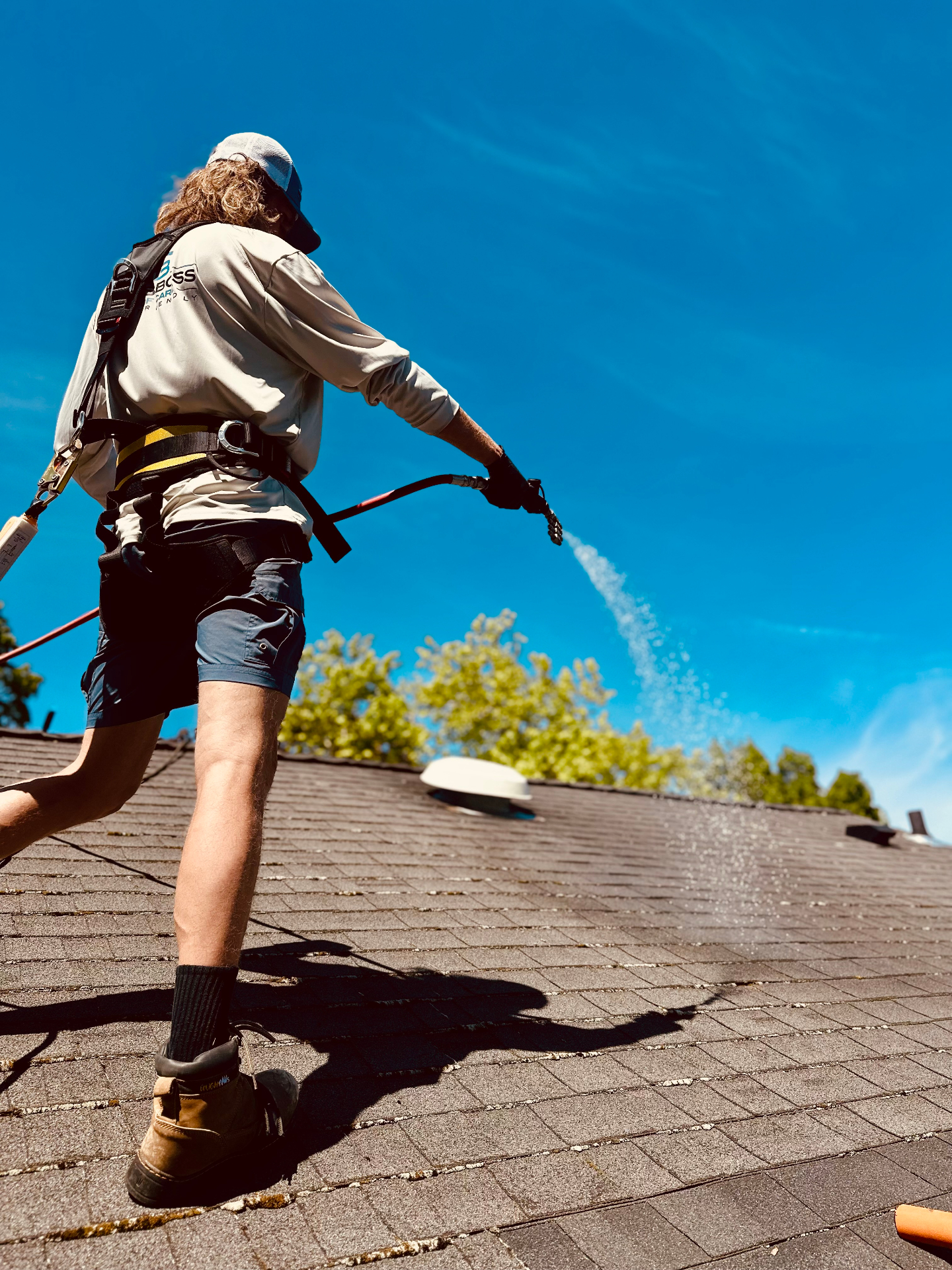 Maarty soft-washing a roof with proper safety harness